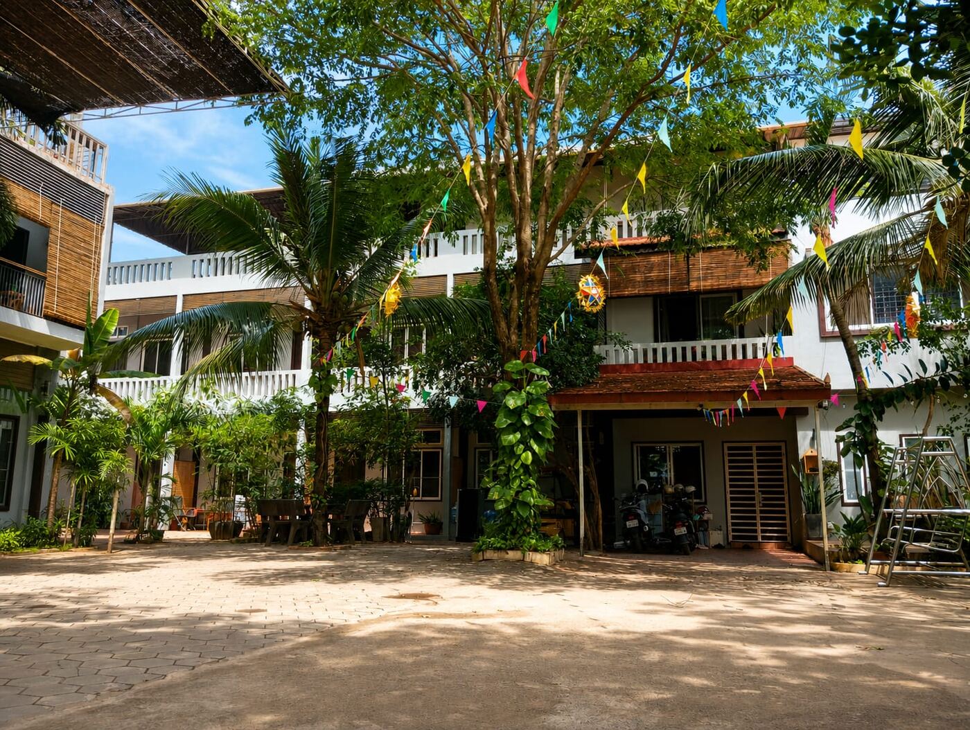 Private courtyard with palm trees, prayer flags and white facade